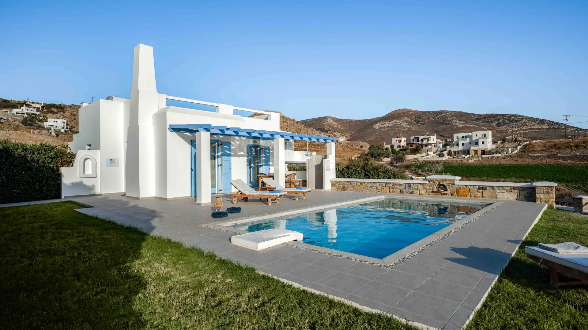 swimming pool area of Luxury Villa Lagoon, surrounded by grass and garden, in Naxos